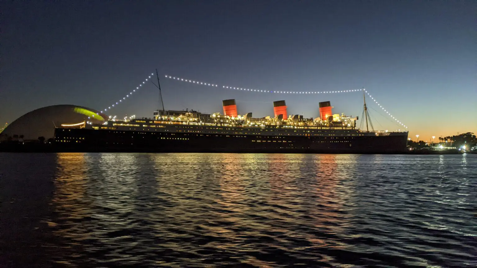 A large ship is lit up at night.
