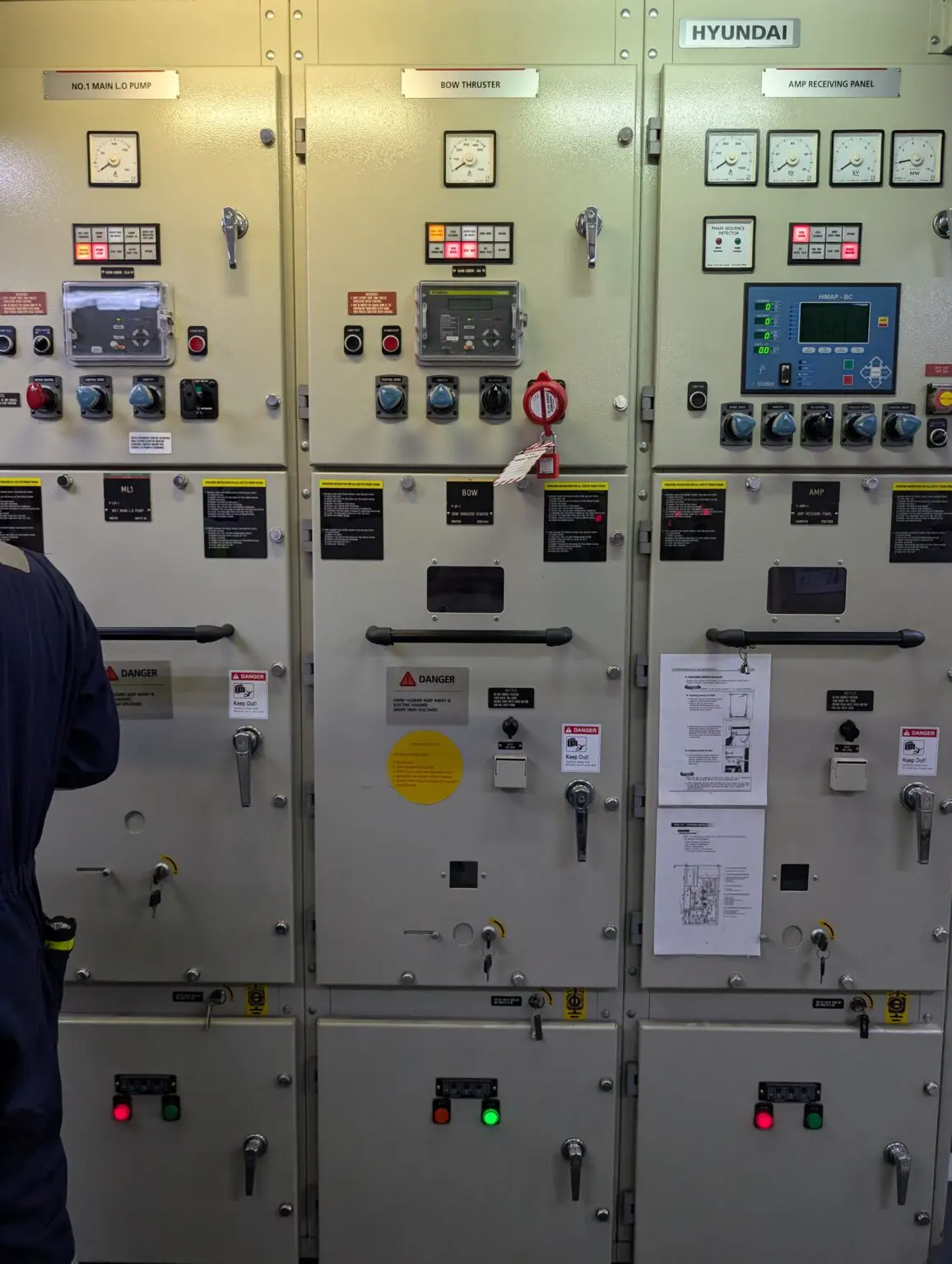 A man standing in front of many electrical panels.